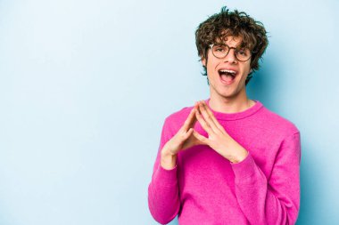 Kafkasyalı genç bir adam mavi arka planda izole edildi. Aklında bir plan kuruyor, bir fikir kuruyor..