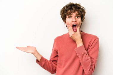 Beyaz arka planda izole edilmiş genç beyaz bir adam bir avuç içinde fotokopi alanı tutuyor, el üstünde tutuyor. Şaşırmış ve mutlu..