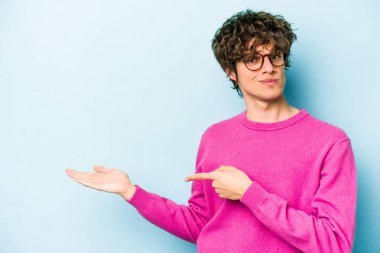 Kafkasyalı genç adam mavi arka planda izole edilmiş. Elinde palmiye ağacının bir kopyası olduğu için heyecanlı..