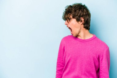 Kafkasyalı genç adam mavi arka planda izole edilmiş. Çok kızgın, öfkeli, hayal kırıklığına uğramış..