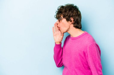 Mavi arka planda izole edilmiş genç beyaz bir adam gizli bir sıcak fren haberi veriyor ve yana bakıyor.