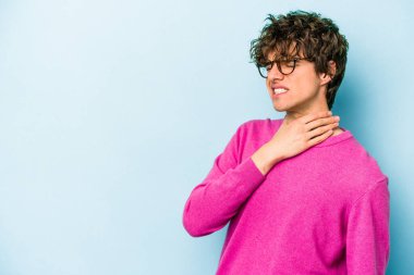 Kafkasyalı genç adam mavi arka planda izole edilmiş kafasının arkasına dokunuyor, düşünüyor ve bir seçim yapıyor..