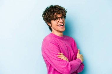 Mavi arka planda izole edilmiş genç beyaz adam mutlu, güler yüzlü ve neşeli.