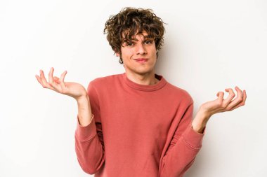 Beyaz arka planda izole edilmiş genç beyaz bir adam sorgulama sırasında omuz silkiyor ve şüphe duyuyor..