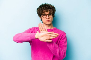 Mavi arka planda izole edilmiş genç beyaz adam elini uzatmış, dur işareti göstererek seni engelliyor..