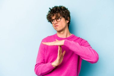 Mavi arka planda izole edilmiş genç beyaz bir adam bir mola hareketi gösteriyor..