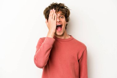 Beyaz arka planda izole edilmiş genç beyaz bir adam yüzünün yarısını palmiye ile örterek eğleniyor..