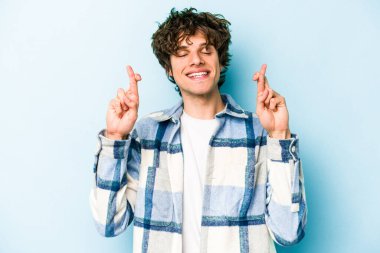 Kafkasyalı genç adam mavi arka planda izole edilmiş şans dilemek için şans diliyor.