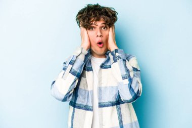 Mavi arka planda izole genç beyaz adam şok oldu, o önemli bir toplantı hatırladı.