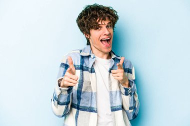 Mavi arka planda izole edilmiş genç beyaz adam öne bakan neşeli gülümsemeler.