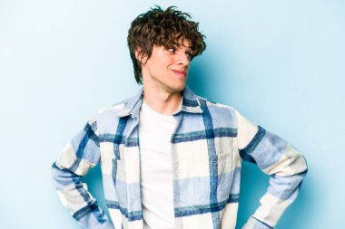 Kafkasyalı genç adam mavi arka planda izole edilmiş hedeflerine ve amaçlarına ulaşma hayali kuruyor.