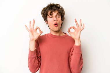 Beyaz arka planda izole edilmiş genç beyaz adam yoğun bir günün ardından rahatlıyor. Yoga yapıyor..