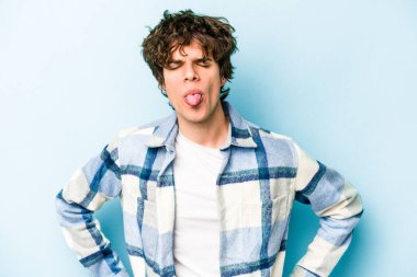 Kafkasyalı genç adam mavi arka planda izole edilmiş komik ve dost canlısı bir dil uzatıyor..