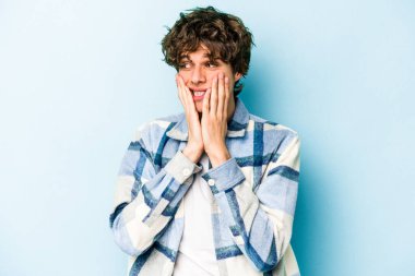 Kafkasyalı genç adam mavi arka planda izole edilmiş korkmuş ve korkmuş..