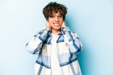 Mavi arka planda izole edilmiş genç beyaz adam öfkeyle bağırıyor..