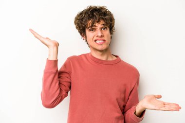 Beyaz arka planda izole edilmiş genç beyaz bir adam. Kafası karışmış ve omuz silkiyor. Kopya alanını tutmak için..