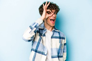 Kafkasyalı genç adam mavi arka planda izole edildi. Heyecanlı görünüyor..