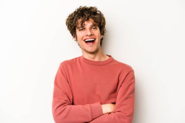 Beyaz arka planda kendini güvende hisseden, kararlılıkla kollarını kavuşturan beyaz tenli genç bir adam..