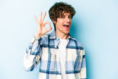 Kafkasyalı genç adam mavi arka planda izole edilmiş neşeli ve kendinden emin..