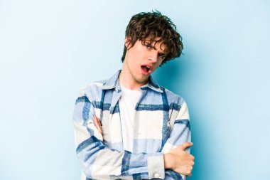 Mavi arka planda izole edilmiş, sıkılmış, yorgun ve dinlenmeye ihtiyacı olan genç beyaz bir adam..