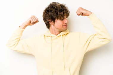 Beyaz arka planda izole edilmiş genç beyaz bir adam güçlü bir hareket gösteriyor, kollarıyla, kadınsı gücün sembolü.