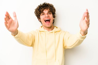 Beyaz arka planda izole olmuş genç beyaz bir adam zaferi veya başarıyı kutluyor, şaşırıyor ve şok oluyor..