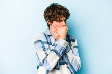 Mavi arka planda izole edilmiş genç beyaz adam virüs ya da enfeksiyon yüzünden boğazında ağrı hissediyor..