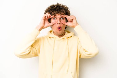 Beyaz arka planda izole edilmiş genç beyaz bir adam bir başarı fırsatı bulmak için gözlerini açık tutuyor..