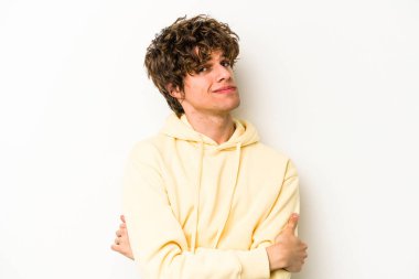 Beyaz arka planda izole edilmiş genç beyaz adam alaycı bir ifadeyle kameraya bakıyor..