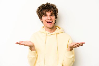 Beyaz arka planda izole genç beyaz adam kollarıyla ölçek yapar, mutlu ve kendinden emin hisseder..