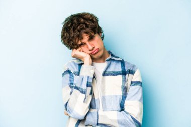 Mavi arka planda izole edilmiş genç beyaz adam tekrarlanan bir görevden yoruldu..