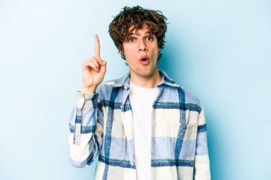 Kafkasyalı genç adam mavi arka planda izole edildi. Harika bir fikri var, yaratıcılık kavramı..