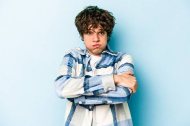 Mavi arka planda izole edilmiş genç beyaz adamın yanakları şişer, yorgun bir ifadesi vardır. Yüz ifadesi kavramı.