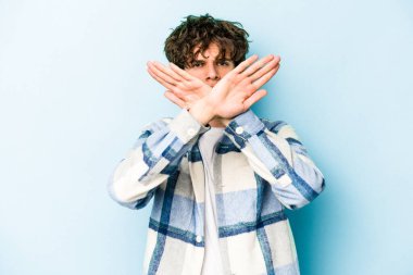 Kafkasyalı genç adam mavi arka planda izole edilmiş bir şekilde inkar hareketi yapıyor.