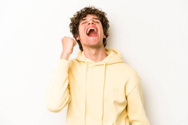 Beyaz arka planda izole edilmiş genç beyaz bir adam zaferi, tutkuyu ve coşkuyu kutluyor, mutlu bir ifade..