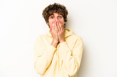 Beyaz arka planda izole edilmiş genç beyaz adam şok olmuş, ağzı ellerle kaplanmış, yeni bir şey keşfetmeye hevesli..