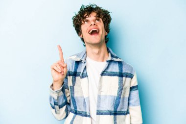 Mavi arka planda izole genç beyaz adam işaret iki ön parmakları boş bir boşluk gösteren.