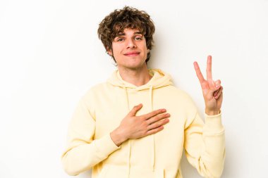 Beyaz arka planda izole edilmiş genç beyaz adam yemin ediyor, elini göğsüne koyuyor..