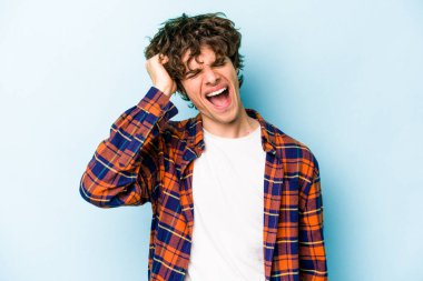 Mavi arka planda izole edilmiş genç beyaz bir adam zaferi, tutkuyu ve coşkuyu kutluyor, mutlu bir ifade..