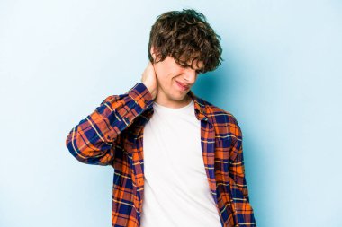 Kafkasyalı genç adam mavi arka planda izole edilmiş. Stres yüzünden boynu ağrıyor. Masaj yapıyor ve elle dokunuyor..