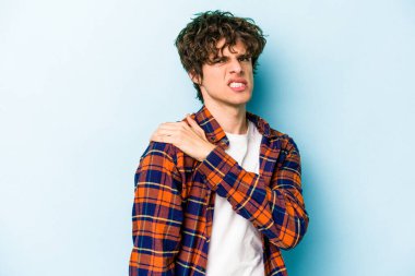 Mavi arka planda izole edilmiş, omuz ağrısı olan genç beyaz bir adam..