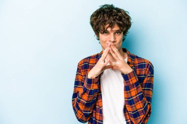 Kafkasyalı genç bir adam mavi arka planda izole edildi. Aklında bir plan kuruyor, bir fikir kuruyor..