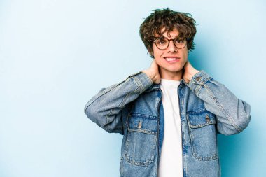 Kafkasyalı genç adam mavi arka planda izole edilmiş kafasının arkasına dokunuyor, düşünüyor ve bir seçim yapıyor..