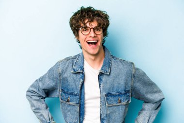 Mavi arka planda izole edilmiş genç beyaz adam mutlu, güler yüzlü ve neşeli.