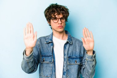Mavi arka planda izole edilmiş genç beyaz adam elini uzatmış, dur işareti göstererek seni engelliyor..