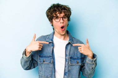 Kafkasyalı genç adam mavi arka planda izole edildi. Parmakları aşağıda, olumlu bir his var..