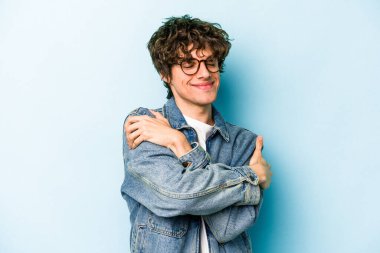 Kafkasyalı genç adam mavi arka planda izole edilmiş, güler yüzlü ve mutlu..