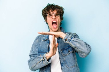 Mavi arka planda izole edilmiş genç beyaz bir adam bir mola hareketi gösteriyor..