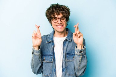 Kafkasyalı genç adam mavi arka planda izole edilmiş şans dilemek için şans diliyor.