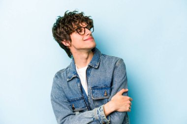 Kafkasyalı genç adam mavi arka planda izole edilmiş hedeflerine ve amaçlarına ulaşma hayali kuruyor.